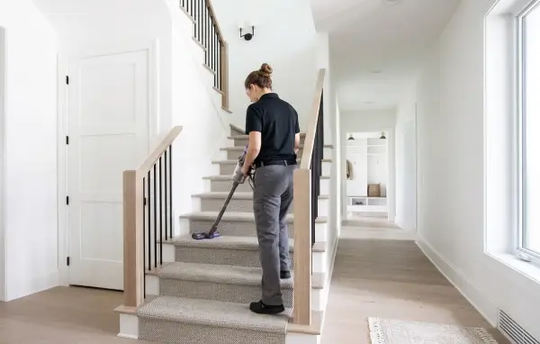 Kanata Cleaners staff member vacuuming a carpeted staircase in a Kanata home